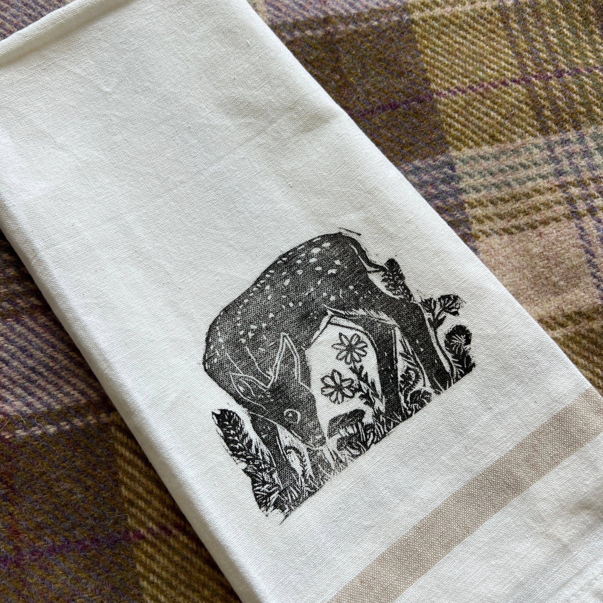 White towel with black fawn design on a plaid fabric background