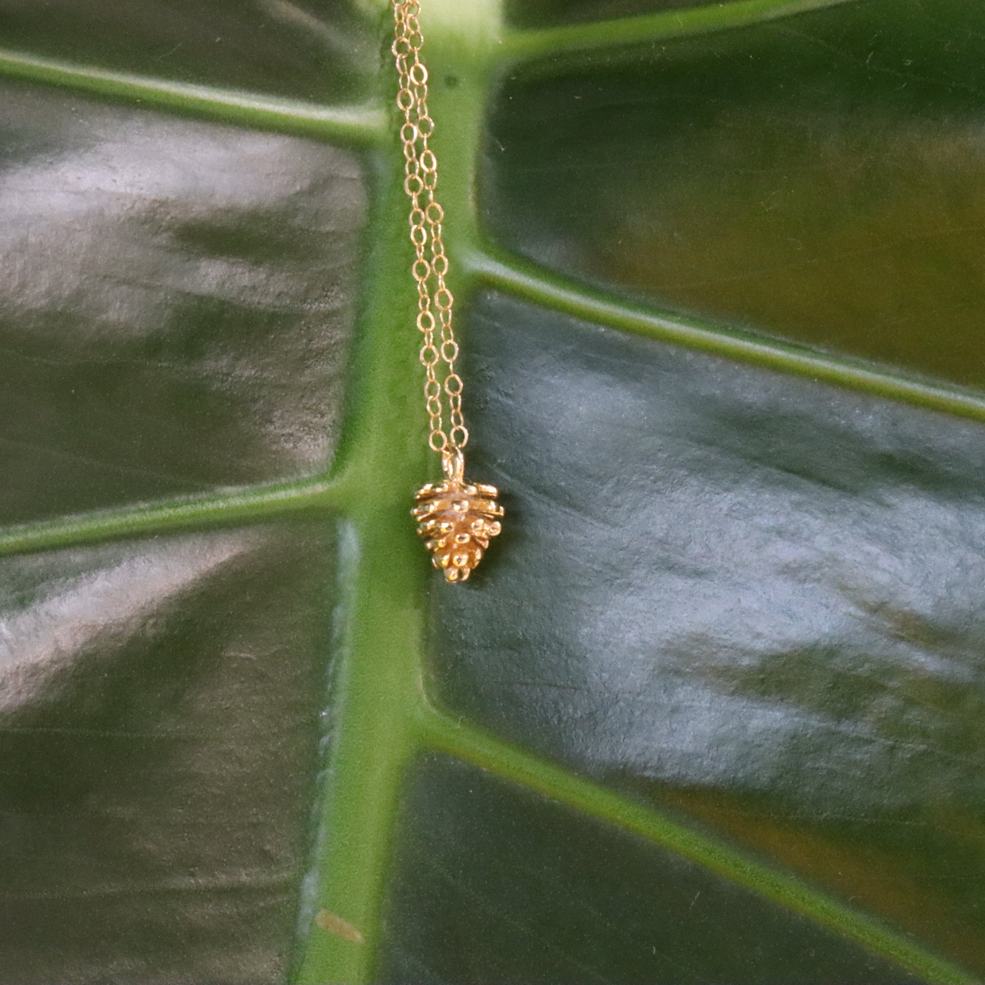 Gold necklace with a pinecone charm pendant
