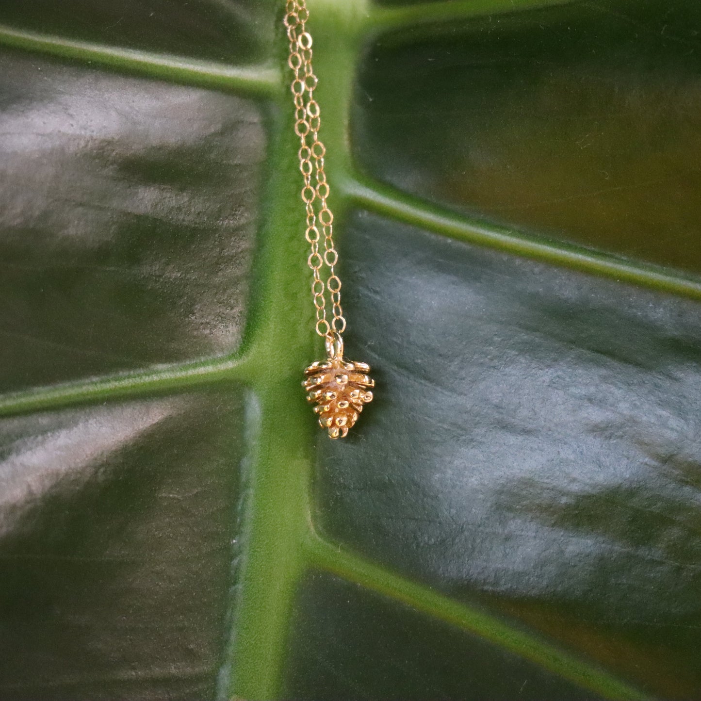 Gold necklace with a pinecone charm