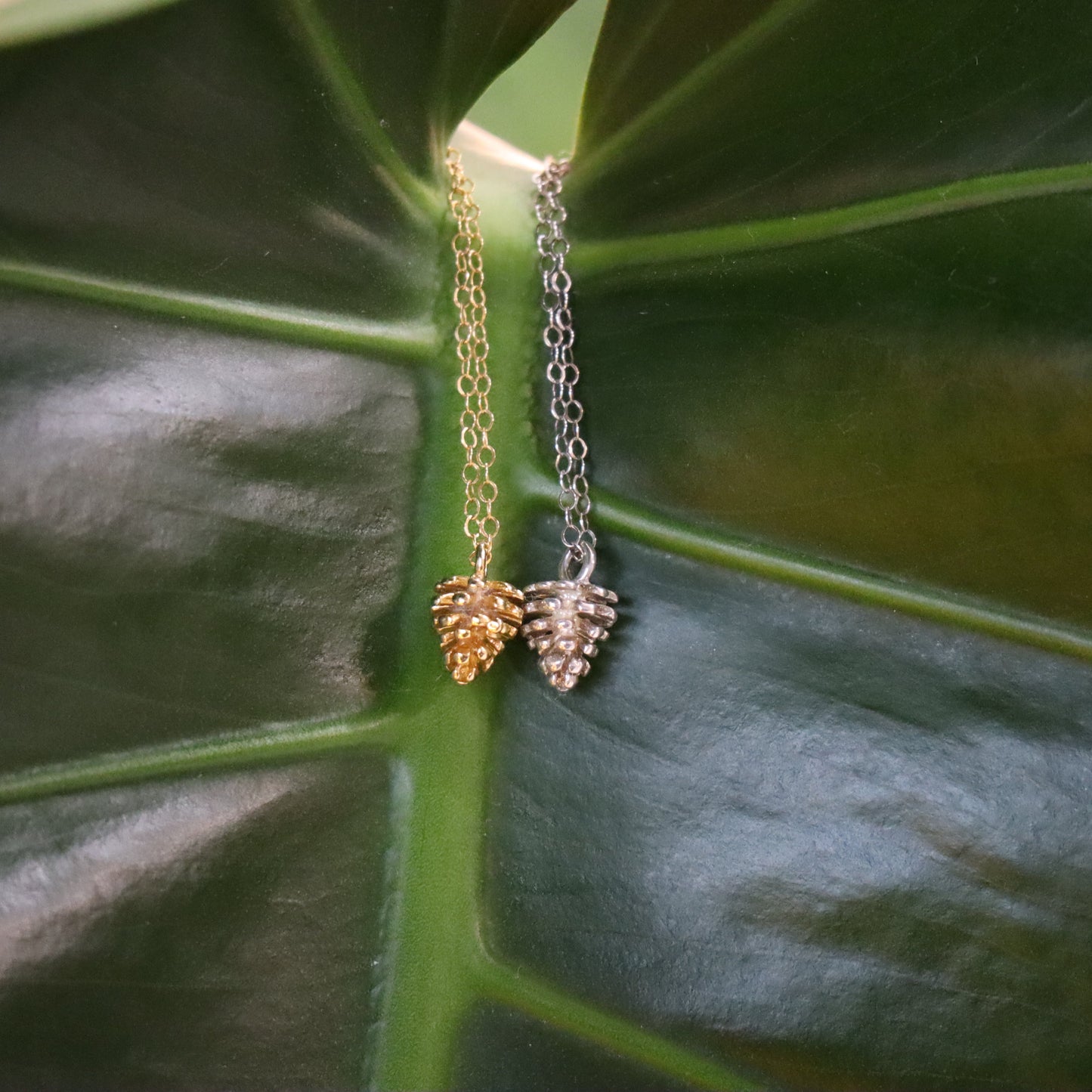 one silver and one gold pinecone necklace