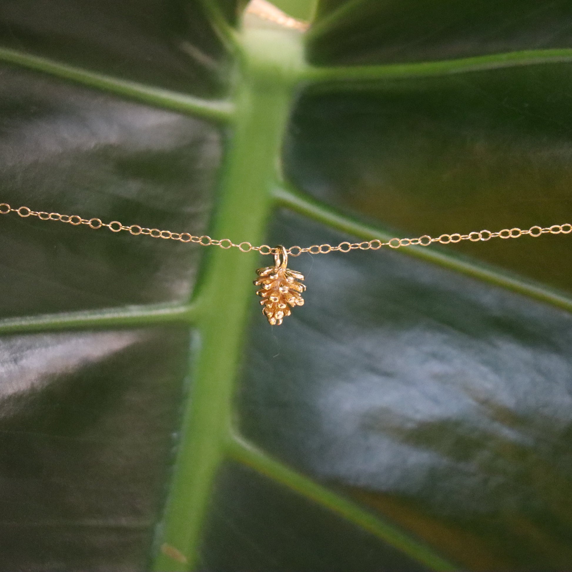 gold necklace with a pinecone charm pendant
