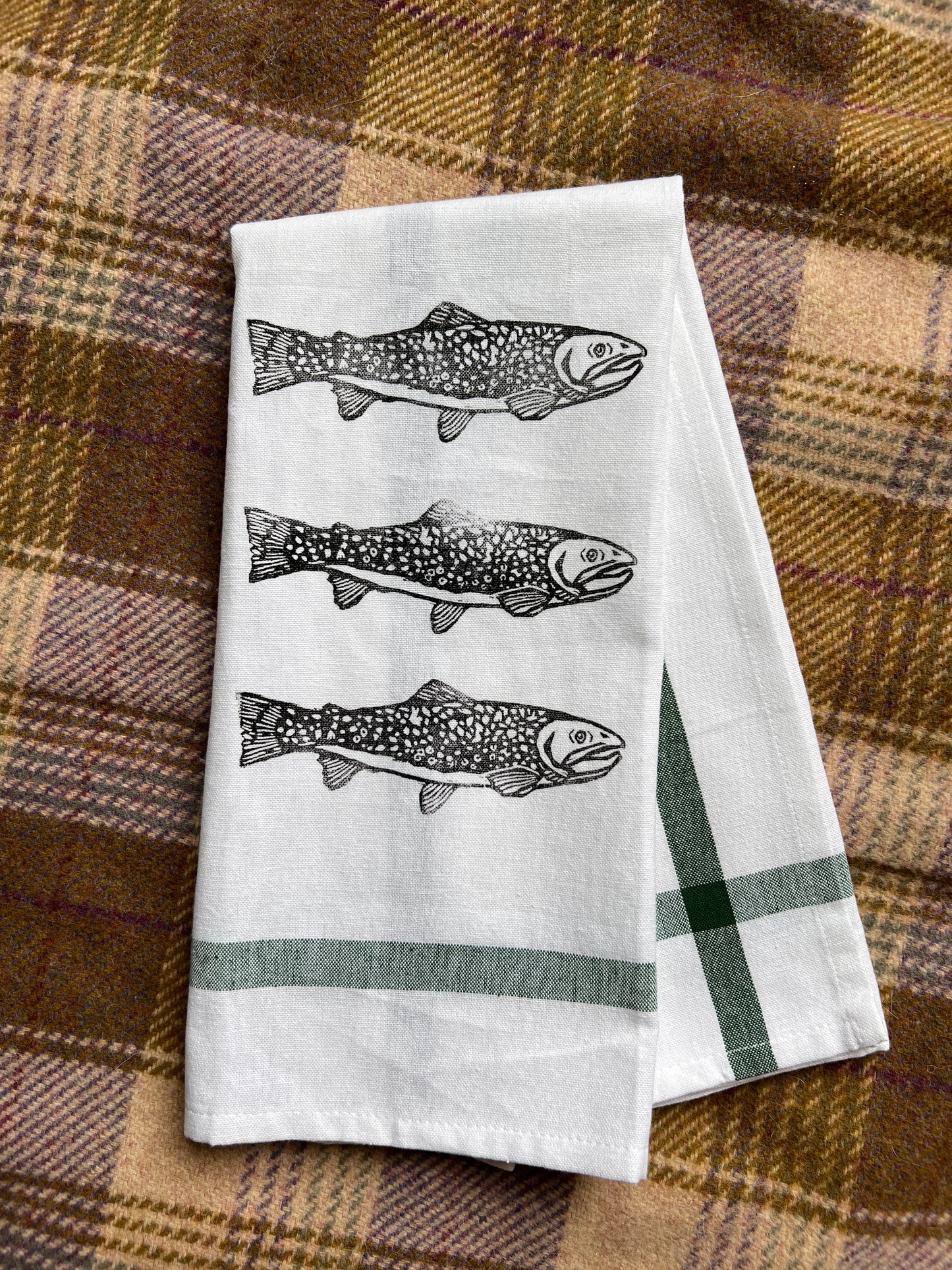 White towel with fish illustrations on a plaid fabric background
