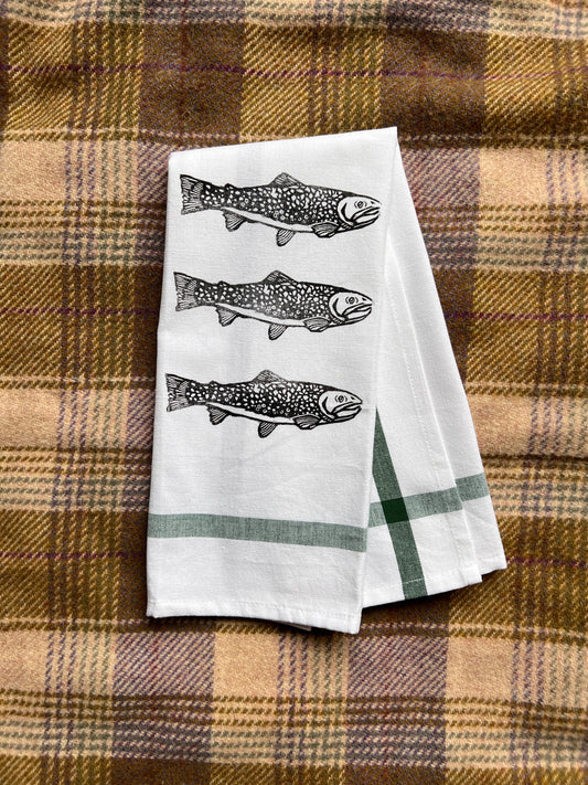 Two white towels with fish design on a plaid fabric background