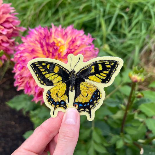 Butterfly-shaped sticker held by a hand with flowers in the background