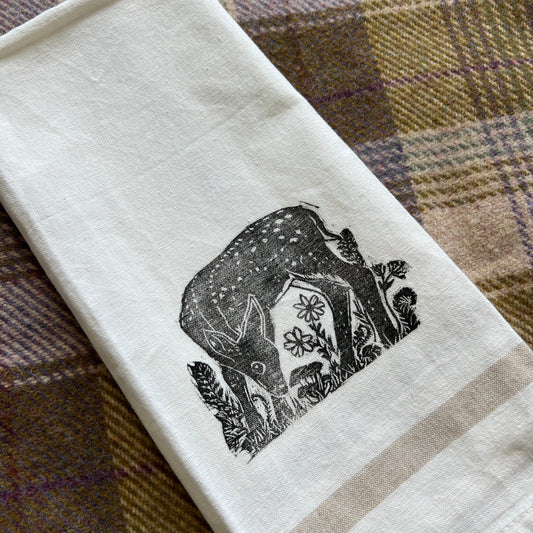 White towel with black fawn design on a plaid fabric background